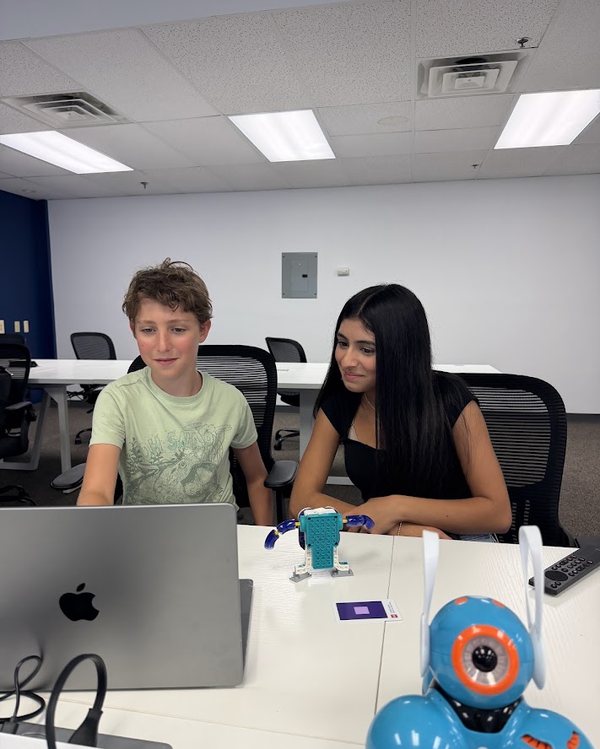 A young student coding a LEGO robot and a Dash robot
